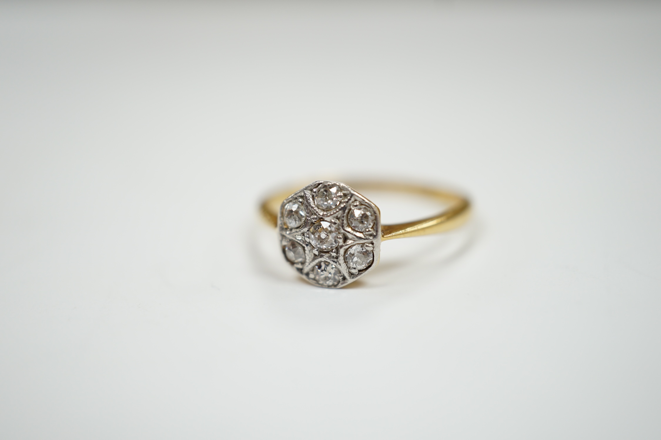 A 1920's 18ct, plat and seven stone diamond set cluster ring, size K, gross weight 2.2 grams.